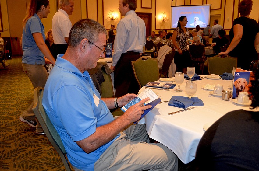 Rick Holden, a director with Southeastern Guide Dogs, reviews the graduation pamphlet.