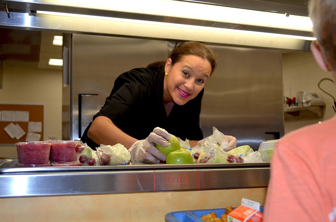 Cafeteria employee Wendy Banks serves up fresh fruit to kindergarten students.