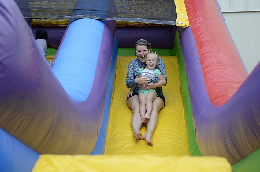 Barb Hagan and daughter Ally, 3, whoosh down an inflatable slide.