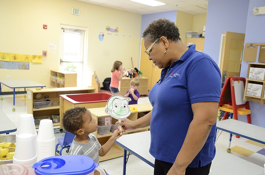 Denita James, the curriculum specialist, praises Kaiden Michael, 3, on his mask.