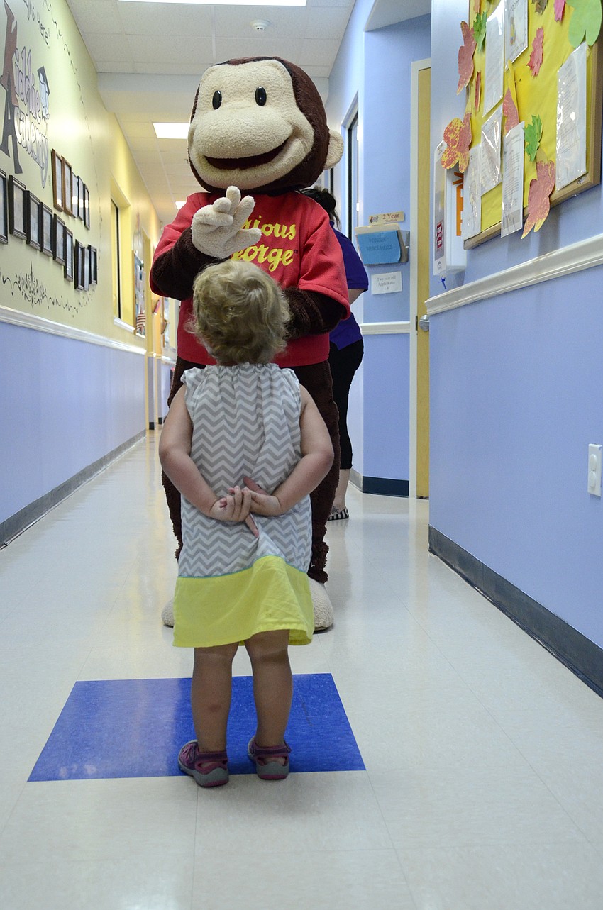 Savannah Grosso, 2, eagerly greets Curious George. 
