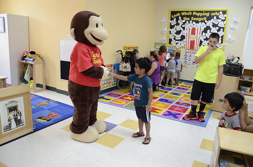 Shivam Patel, 4, shakes hands with Curious George.