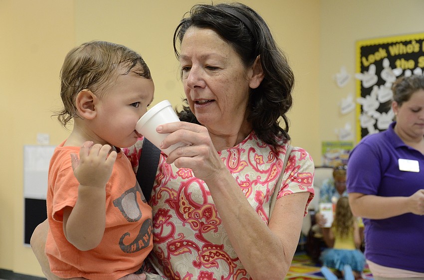 Zachary Greene, 1, gets a drink of water with a little help from Helen Greene, his grandmother.