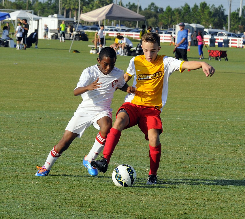 Blake Benton of the Lakewood Ranch Chargers battles a Clay County midfielder for possession.