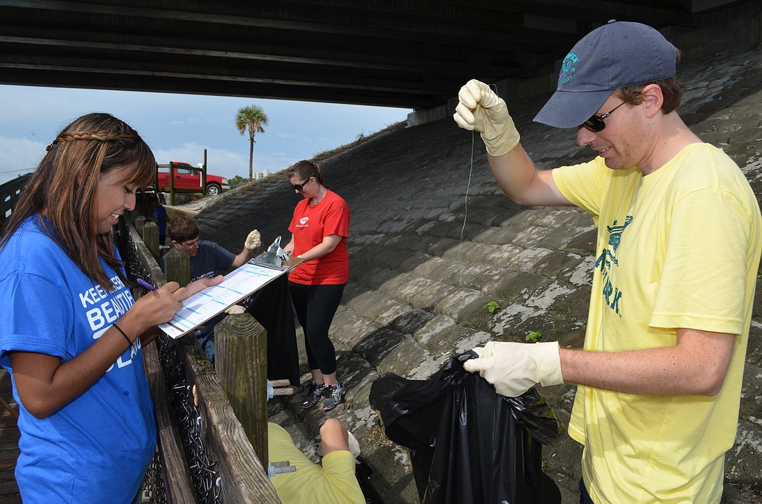 Veronica Hernandez records trash findings with Michael Comes during the Young Professional Group's clean up of Overlook Park in 2014.