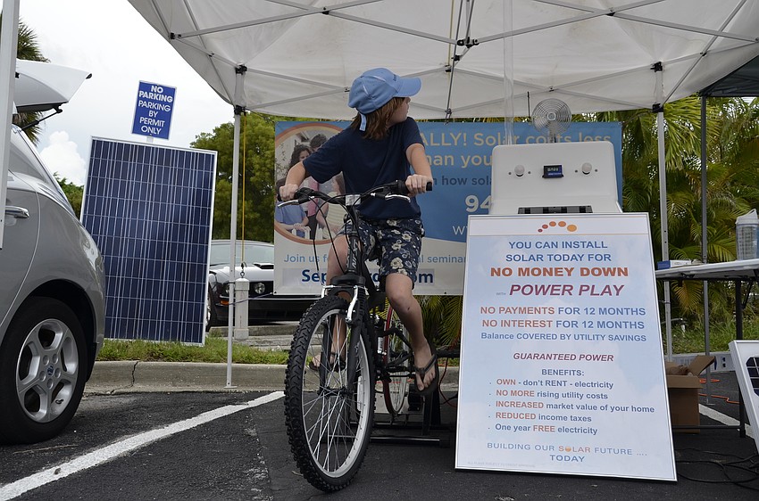 Felix Lange pedals to lift a pingpong ball up the tube in the Region Solar booth.