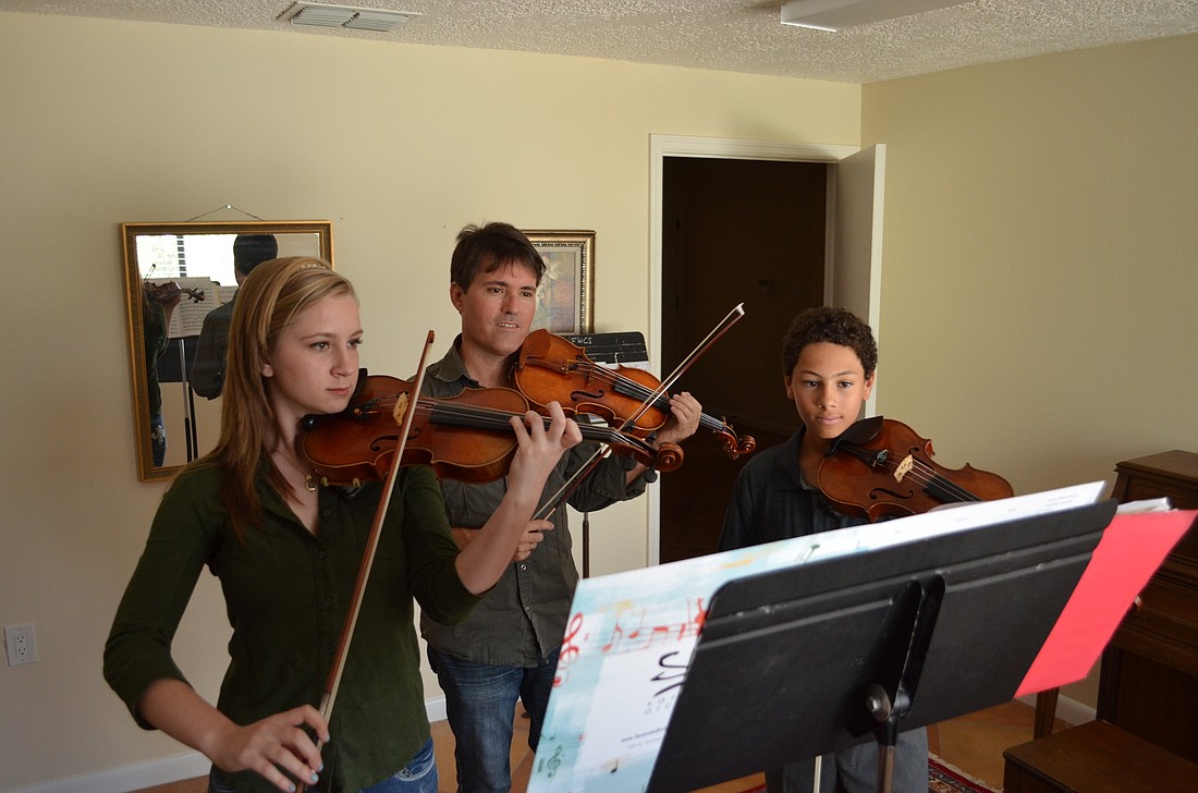Sarasota Music Conservatory co-founder Sean O'Neil (middle) leads students Sommer Altier and Giordano Scarano in a violin lesson.