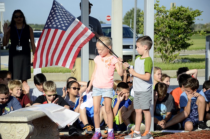 Kindergarteners Vera Dalhsten and Peyton Hale hold the flag during the Pledge of Allegiance.