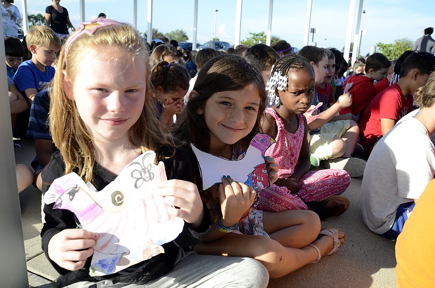 Second-graders Jayden Brown and Nateline Sejaan-Clark hold up their peace doves during the assembly.