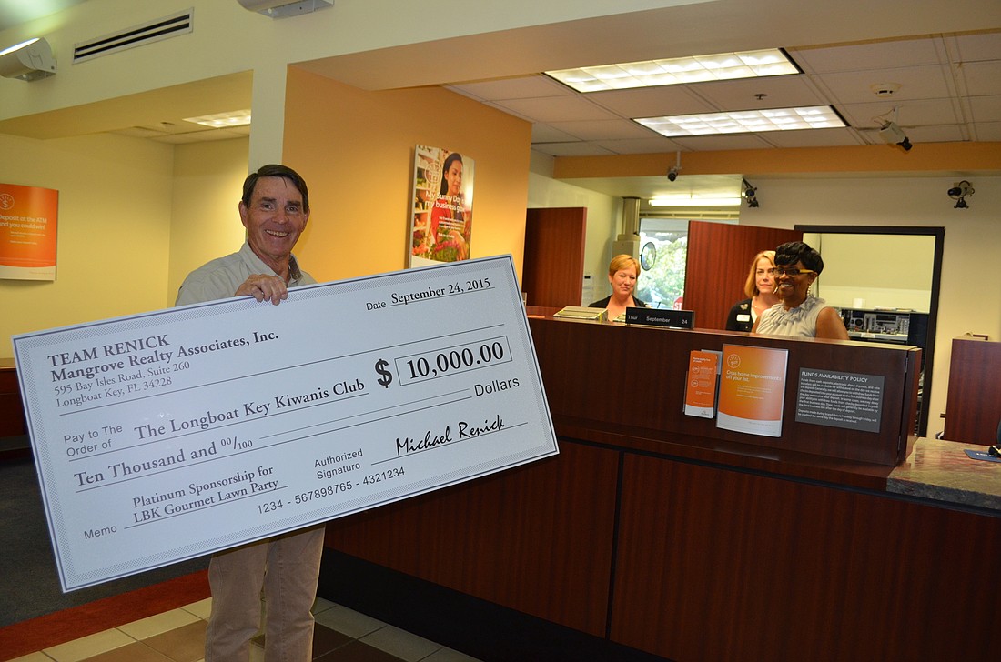 Kiwanis Club Treasurer Jim Larson deposits Team Renick's $10,000 Platinum Partner Check.