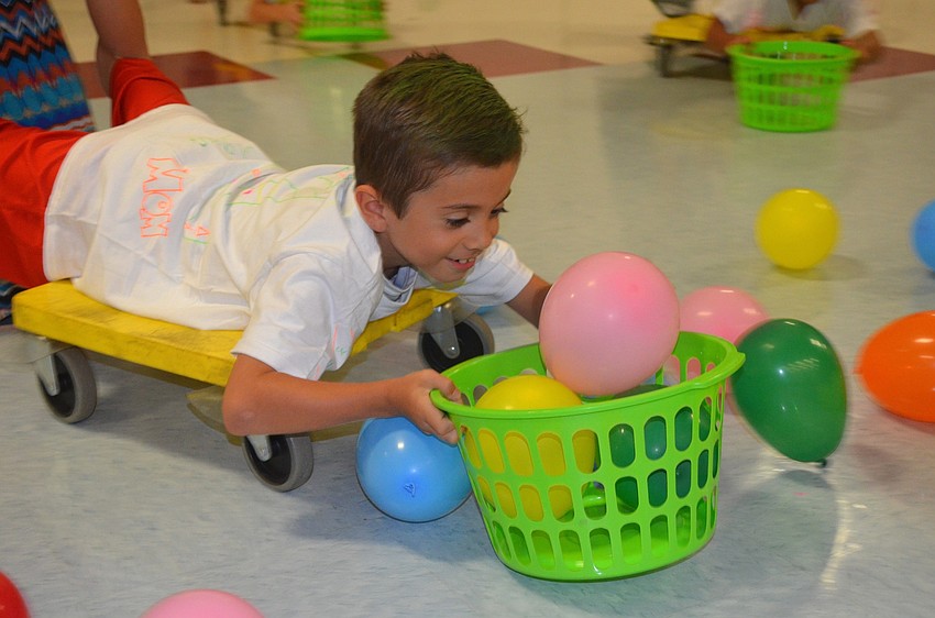 Brayden Berg collects balloons while his mother pushes him.