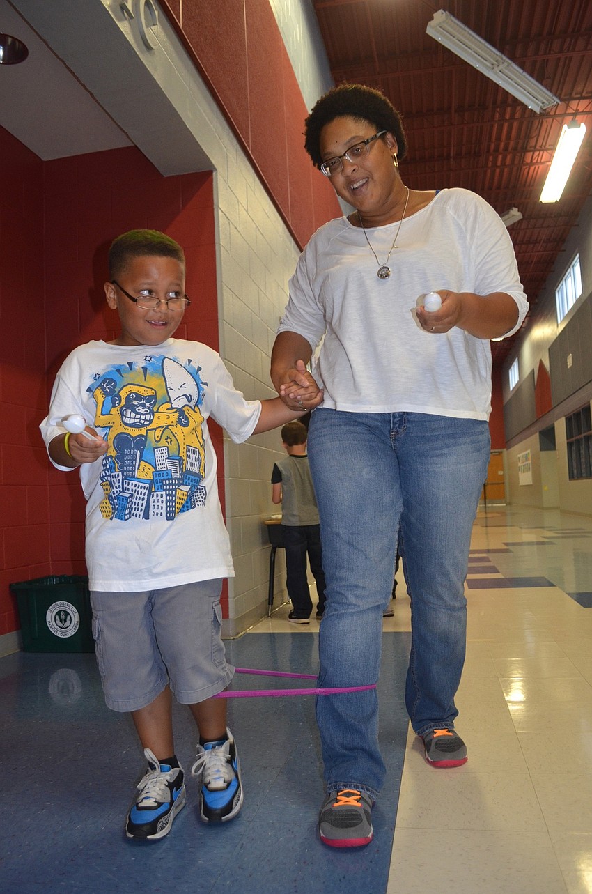 Carter and Chanelle Fields carefully carry eggs on spoons while quickly walking down the hall.