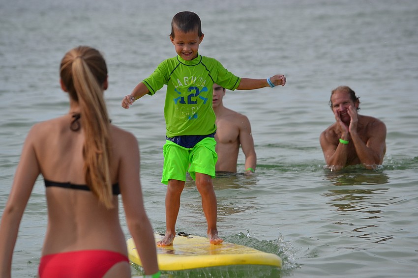Volunteer Patrick Ryan cheers on Gabriel Bishop as he finds his balance on a wave.
