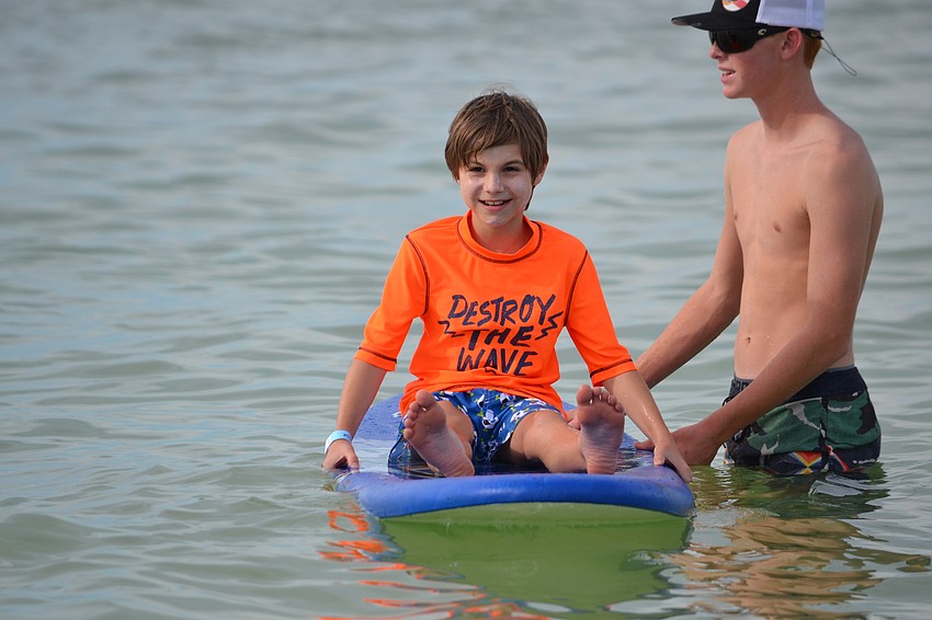 Hayden Joyner smiles to his parents on the beach as he waits for a wave to come in.