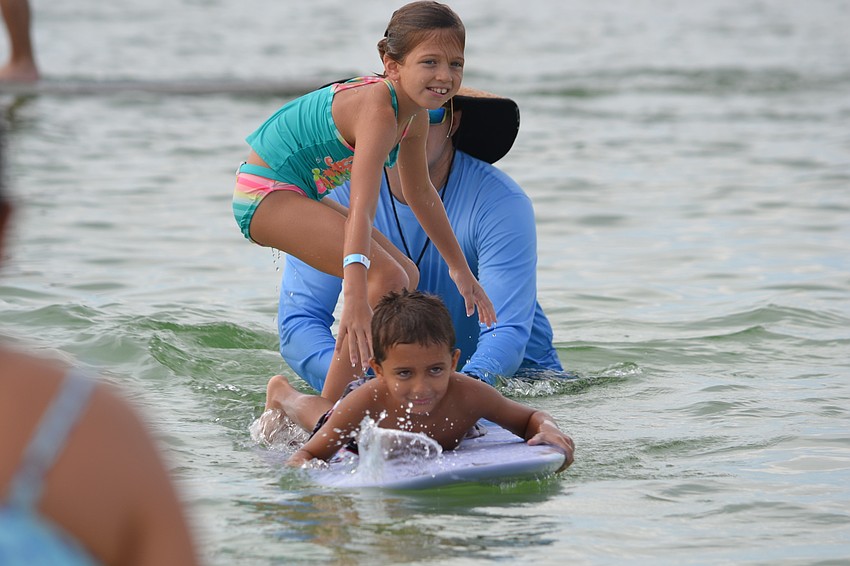 Siblings Sophia and Luciano Iannotti share the board for a wave.
