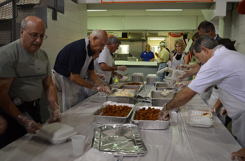 Rotarians prepare boxes with hush puppies, barbecue pork, coleslaw and black-eyed peas.