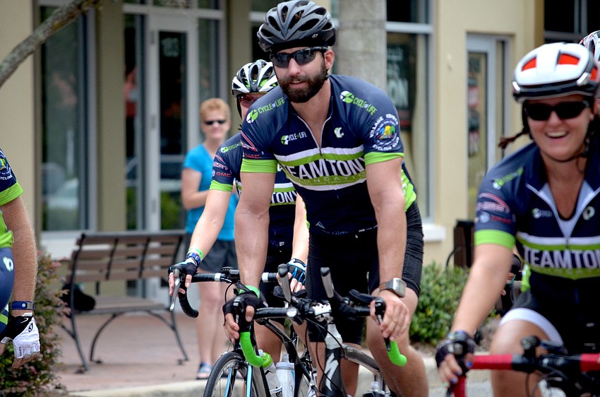 Cody Moss cycles toward his family, who is waiting for him on Main Street.