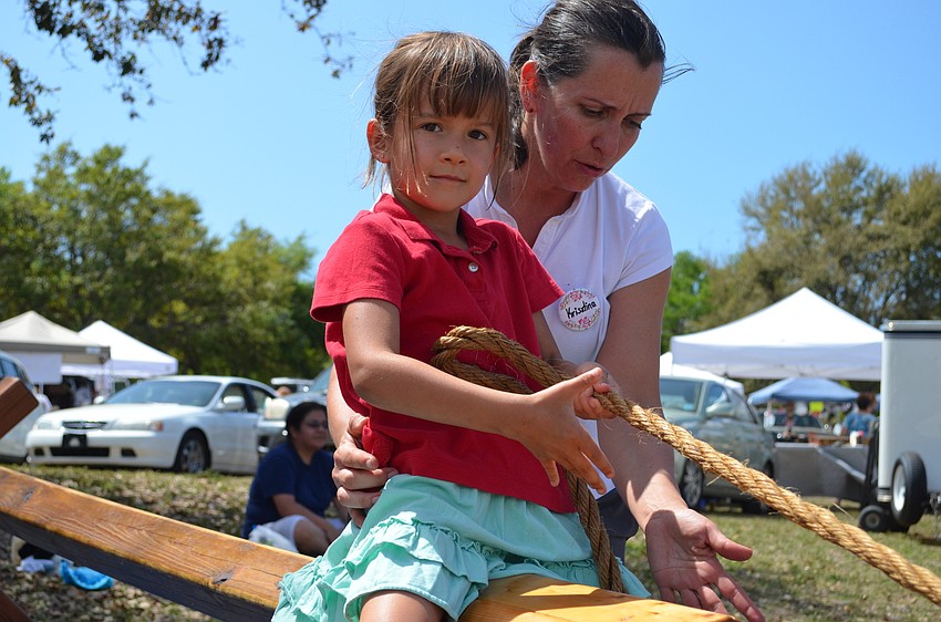 Anabel Procel takes a turn on the barrel horse game with assistantance from Kristina Ihaszy at the Phillippi Farmhouse Market. Megan Swick plays a fishing game with her son Bernard.