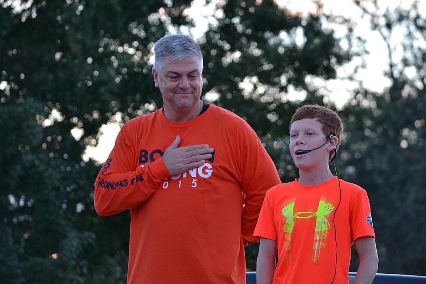 John Cox looks on as Dylan Bechtold sings the national anthem.