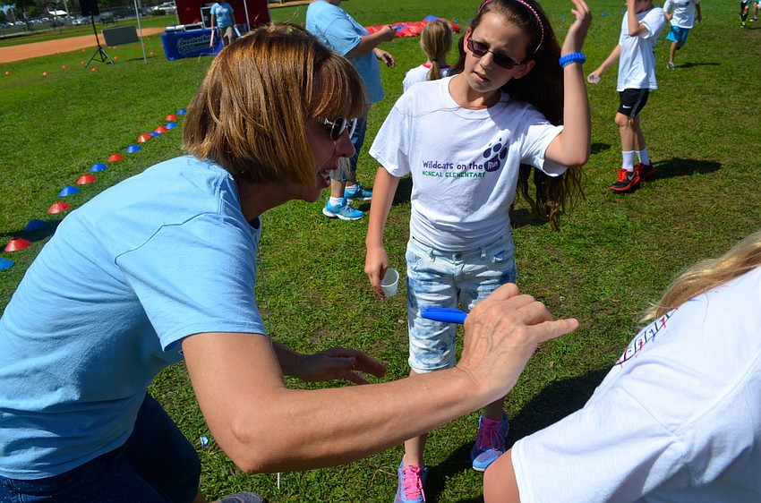 McNeal Elementary Principal Norma Scott checks off laps accomplished on students' shirts.