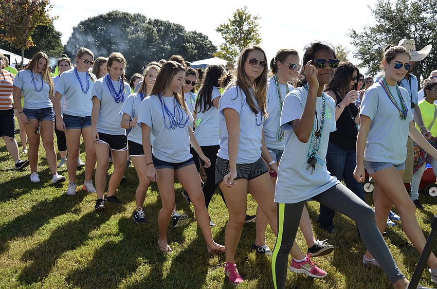 The La Sertoa community service society of Sarasota High School dances to the Cupid Shuffle before the walk.