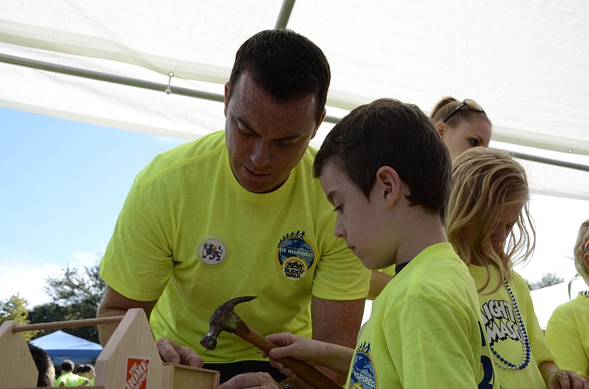 Sarasota resident Reiss Holsbeke helps his son Jayden build a toolbox at the Home Depot booth.