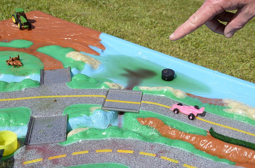 Ross Peterson with Florida Friendly Landscaping points out the drainage of fertilizer into a water source in this water shed model.