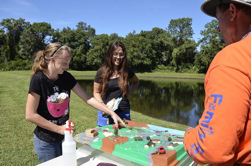 Tara Haight and Dawn Wishiewski with Pinnacle Academy test out the watershed model with Ross Peterson from Florida Friendly Landscaping.