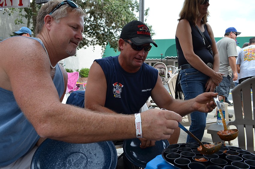 Chris O' Connor and Todd Flagg scoop chili into cups for attendees to sample.