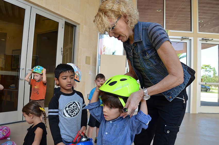 The Gan teacher Jackie Newville helps Daniel Fine put on his helmet.