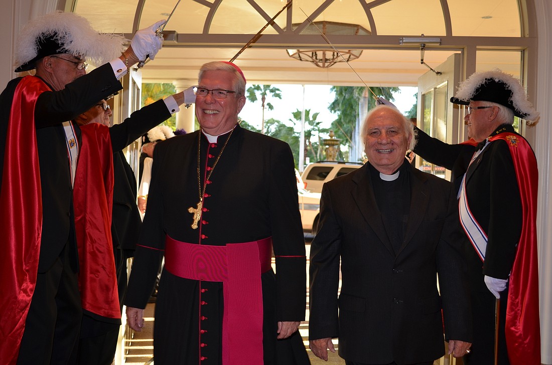 Bishop Frank Dewane and Father Fausto Stampiglia enter beneath the swords of the Knights of Columbus.
