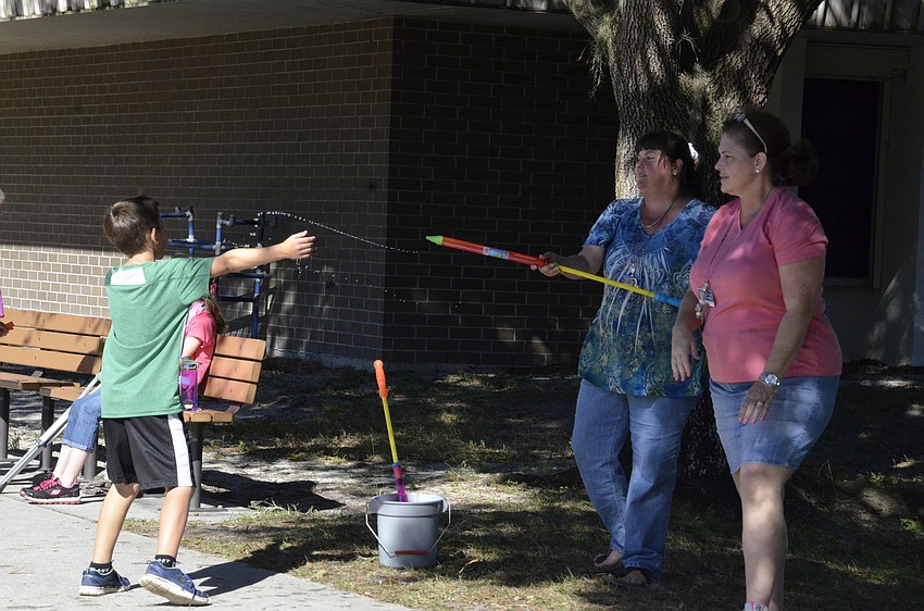 Matthew Tabor gets squirted with a water shooter by third-grade teachers Cami Tabor and Kim Hoy.