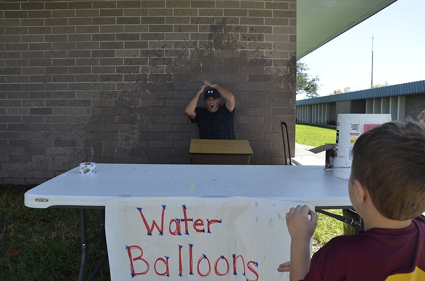 Landen McCutchan drenches third-grade teacher Charles Rogalla  with a water balloon.