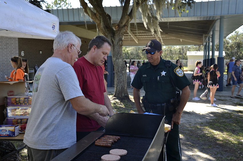 Sid Royce helps his son and Tara principal Steve Royce cook hotdogs, under the supervision of Manatee County Sheriff's Office Deputy John Kruse.