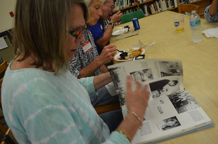 Sandie Gettleson turns the pages looking for photos of her husband David in the 1967 Cardinal Mooney Catholic High School yearbook.