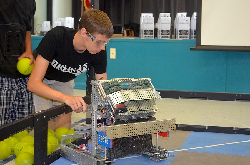 Braden River High student Brantley Deines loads a machine with tennis balls.