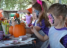 Sisters Leila and Brynlee Brewer pain pumpkins together.