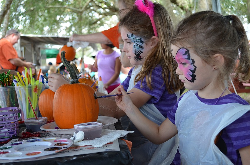 Sisters Leila and Brynlee Brewer pain pumpkins together.