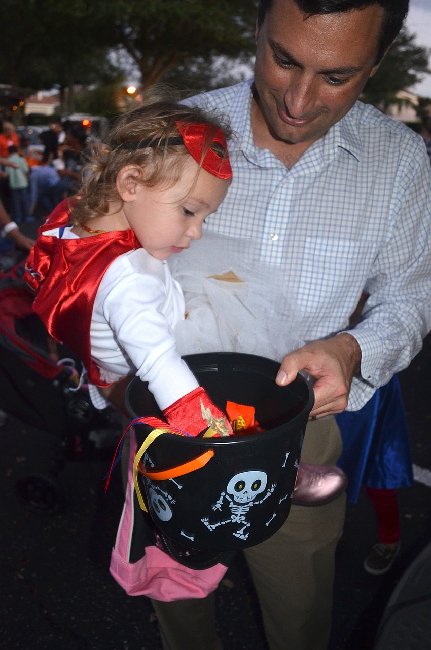 Alexis Truxton grabs candy with the help of her father, Dave.
