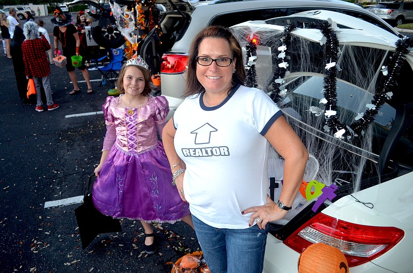 Audrey O'Neil gathers candy, while her mother, Suzanne, distributes candy by her decorated car.