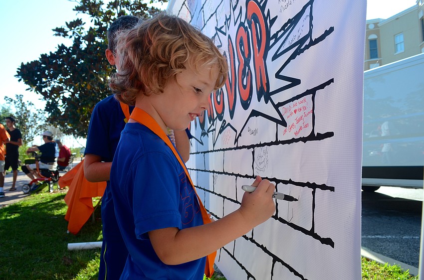 Three-year-old Conner Stablein signs a banner to support finding a cure for MS.