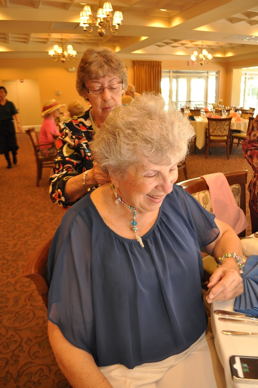 Theresa Colozza helps Marilyn Zynda put on her necklace.