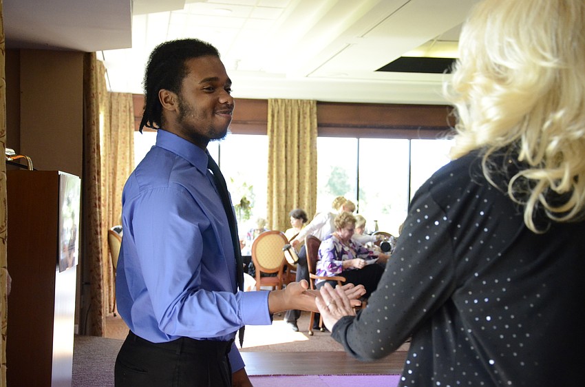 Brand Guzman, a State College of Florida student and scholarship recipient, helps Melodie Dickerson on stage.