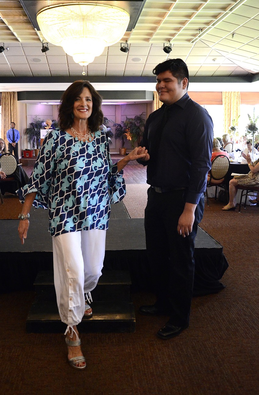 Sandy Homko gets a hand down from the runway from Michael Evans, a State College of Florida student and a club scholarship recipient.