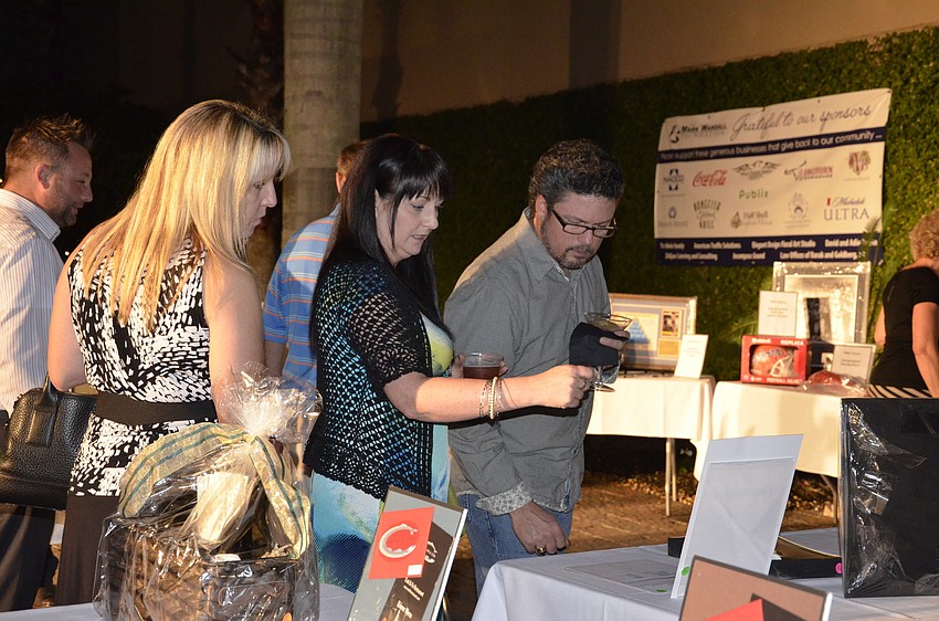 Angie Garland of Lakewood Ranch and Toni and Bill Booth of Bradenton check out the silent auction baskets.