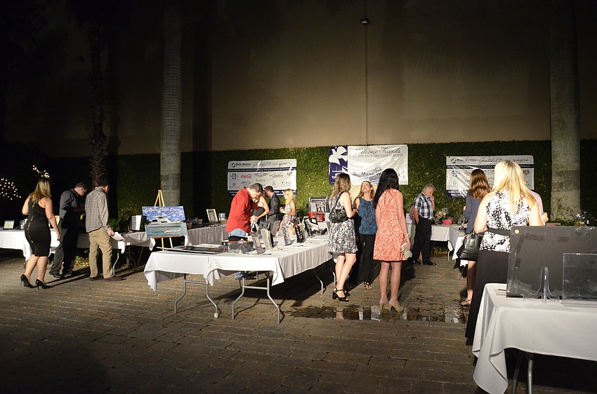 Guests milling outside examine the silent auction items.