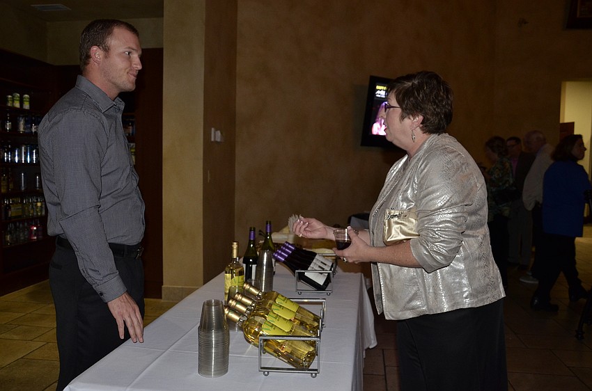 Robin Rothenbach, a volunteer from Sarasota, talks with Nena Alsaker of North Carolina about the wine selection.
