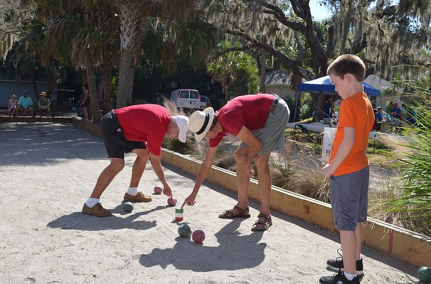 Christopher Austin learns how to play bocce ball from Tom Hurban and Jerry Hall.