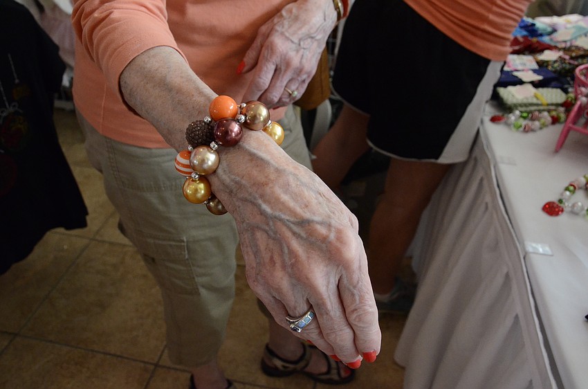 Lorie Bavin of Louisville, Ken., tries on a bracelet from GreyHawk resident Debbie Romano's booth, Keepsake Konnection. Bavin came to GreyHawk to visit her niece, Brittany Biermann.