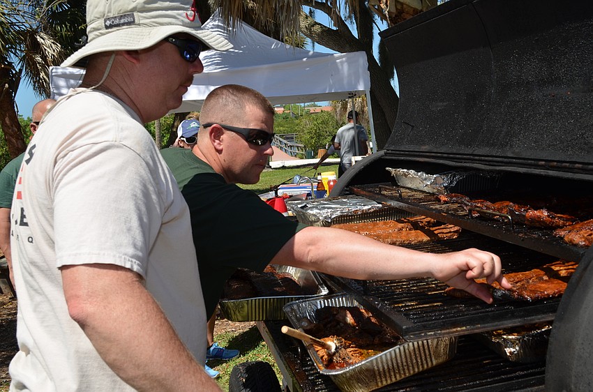 Glen Snyder and Jason Cook of Station 1 rotate ribs on a grill.